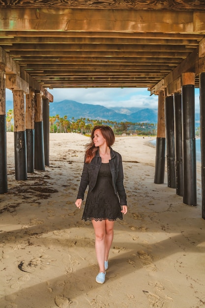 junge frau mit langen haaren steht in der nähe des piers am strand in santa barbara kalifornien usa