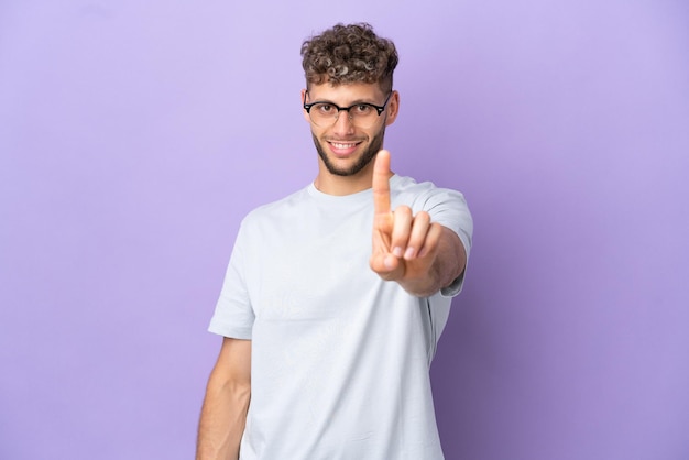 Junge Frau mit langen Haaren über isolierter gelber Wand, die mit dem Finger zur Seite zeigt