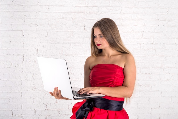 Junge Frau mit Laptop auf Backsteinmauer