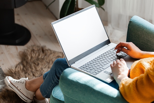 Junge Frau mit Laptop-Bildschirm leer, Mock-up, Arbeit zu Hause