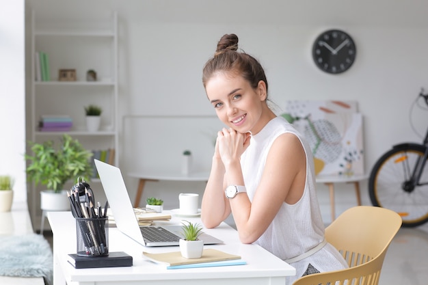 Junge Frau mit Laptop, die zu Hause arbeitet