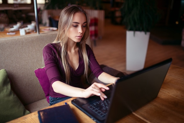 Junge Frau mit Laptop im Café.