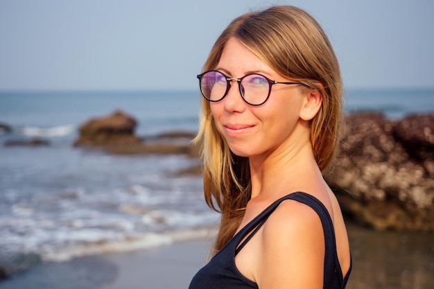 Junge Frau mit Laptop im tropischen Urlaub, die auf der Veranda des Sommercafés am Strand am Meer sitzt