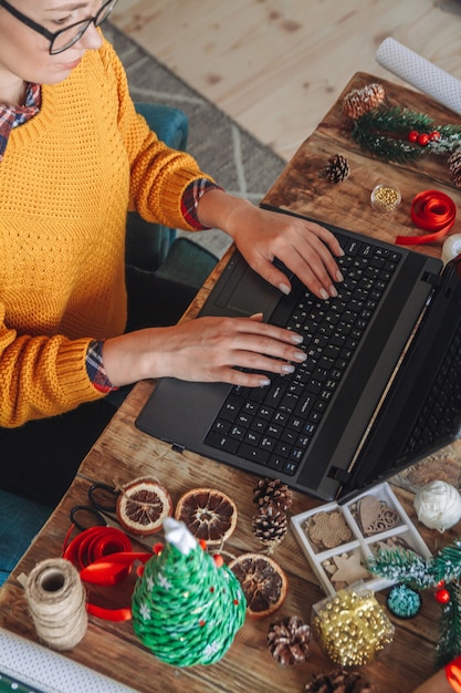 Junge Frau mit Laptop wählt Neujahrsgeschenke