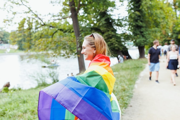 Junge Frau mit LGBTQI-Stolz-Regenbogenfahne auf der Straße im Park Pride Month-Konzept