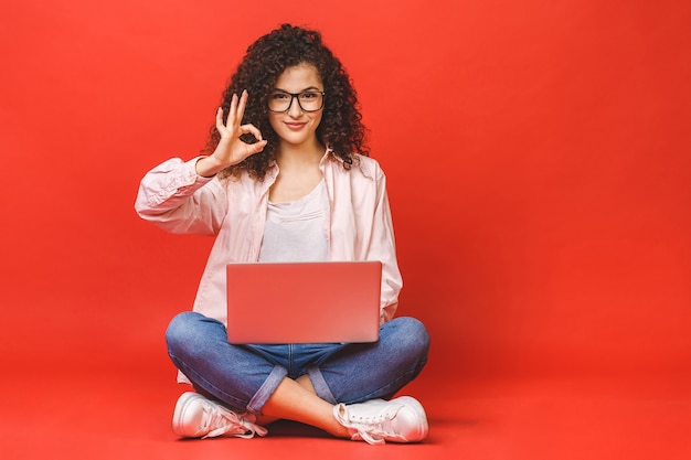 Junge Frau mit lockigem Brunethaar mit Laptop