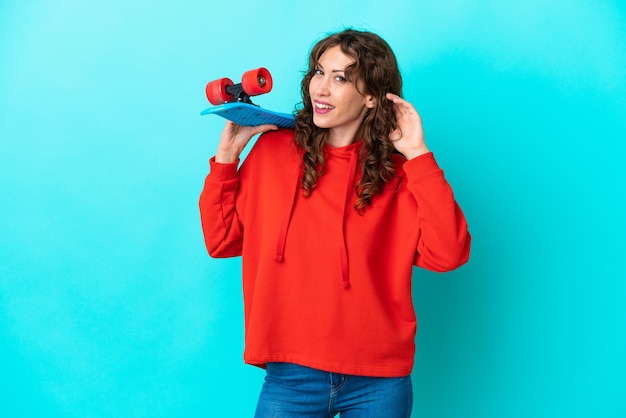 Junge Frau mit lockigem Haar auf blauem Hintergrund mit einem Schlittschuh isoliert