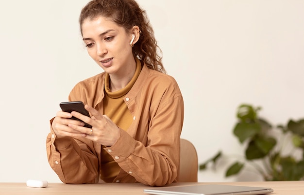 Junge Frau mit lockigem Haar unter Verwendung des Mobiltelefons