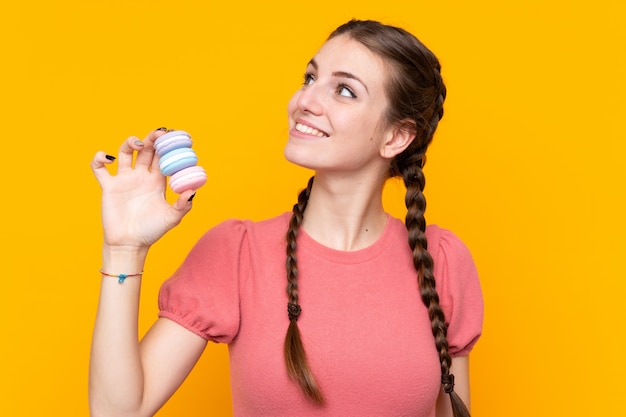 Junge Frau mit macarons über lokalisierter Wand