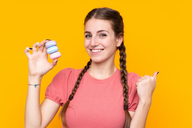 Junge Frau mit macarons über lokalisierter Wand