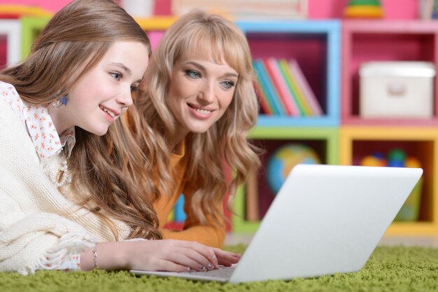 Junge Frau mit Mädchen mit Laptop zu Hause auf dem Boden