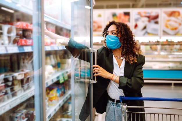 Junge Frau mit Maske kauft im Supermarkt Einkaufen während der Pandemie