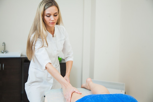 Junge Frau mit Massage im Beauty-Spa-Salon Kosmetikerin massiert weibliche Beine Bodycare-Konzept
