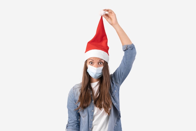 Junge Frau mit medizinischer Telefonmaske und Weihnachtsmütze. Weihnachtseinkäufe online in Quarantäne. Hochwertiges Foto