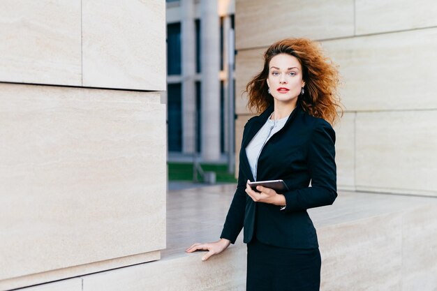 Junge Frau mit Mobiltelefon, während sie an der Wand steht