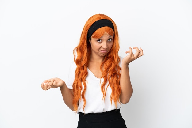 Junge Frau mit orangefarbenen Haaren auf weißem Hintergrund, die beim Anheben der Schultern Zweifel macht