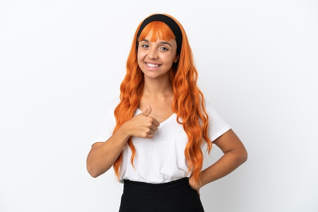 Junge Frau mit orangefarbenen Haaren auf weißem Hintergrund, die eine Geste mit dem Daumen nach oben gibt