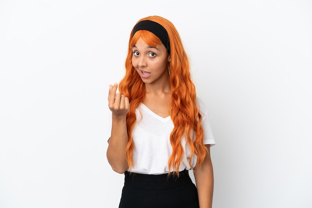 Junge Frau mit orangefarbenen Haaren isoliert auf weißem Hintergrund, die Geldgeste macht