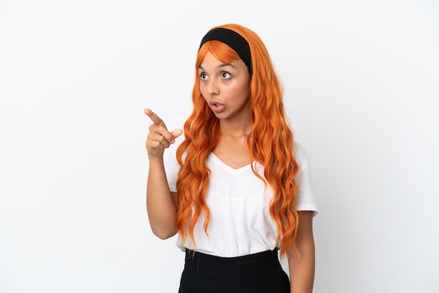 Junge Frau mit orangefarbenen Haaren isoliert auf weißem Hintergrund, die wegzeigen