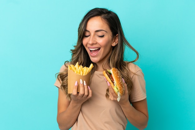 Junge Frau mit Pommes Frites und Burger über isoliertem Hintergrund