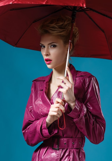 Junge Frau mit Regenschirm auf Blau