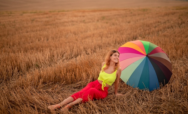 Junge Frau mit Regenschirm im Feld