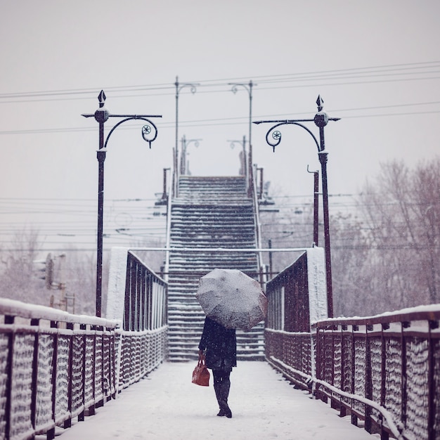 Junge Frau mit Regenschirm im Schneefall, Retro-getöntes Bild