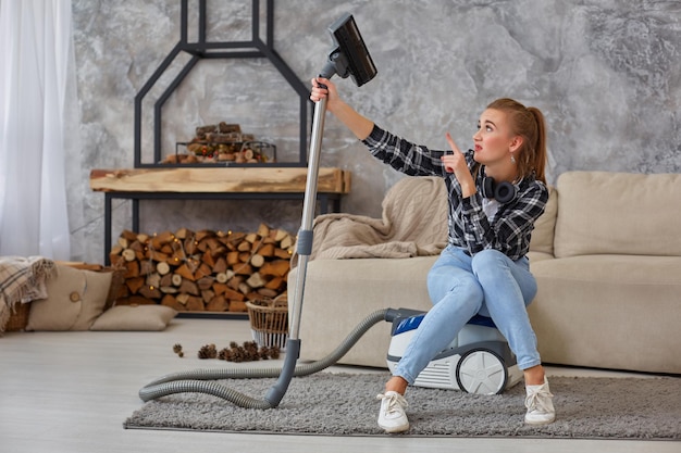 Junge Frau mit Reinigungsgeräten bereit, das Haus zu reinigen, auf der Couch sitzend. Professionelles Reinigungskonzept, Kopierraum. Ermüdung