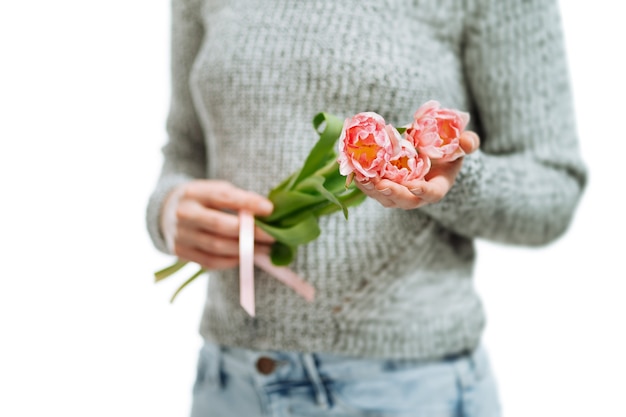 Junge Frau mit rosa Tulpen auf weißem Hintergrund. Unschärfeporträt, Nahaufnahme, Kopienraum, selektiver Fokus.