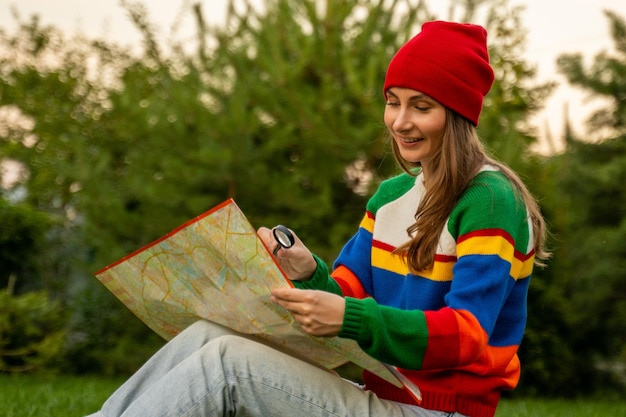 Junge Frau mit rotem Hut überprüft die Karte Eine kaukasische Frau untersucht eine Karte mit einem Vergrößerungsglas