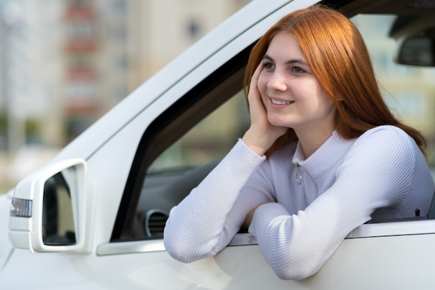 Junge Frau mit roten Haaren, die ein Auto fahren