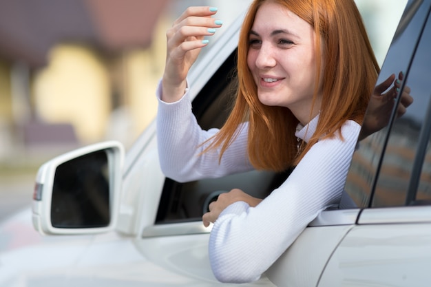 Junge Frau mit roten Haaren, die ein Auto fahren.