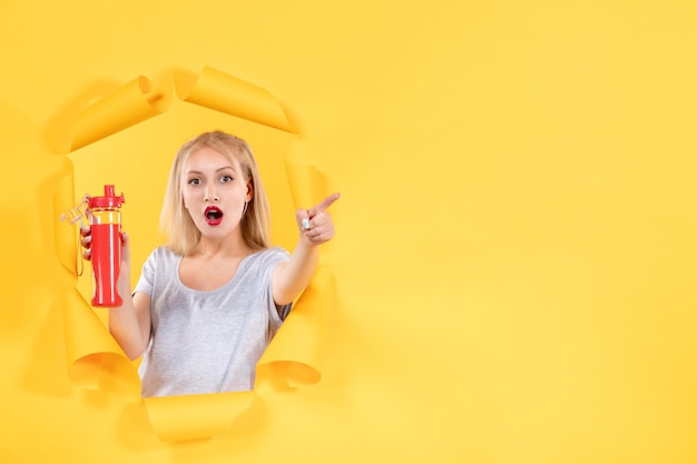 Junge Frau mit roter Flasche auf gelbem Schreibtisch Athlet Gesichtsfitness-Sporthalle