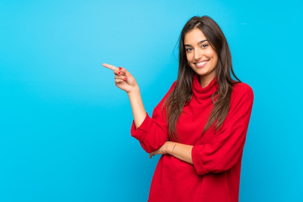 Junge Frau mit roter Strickjacke lokalisierte den blauen Zeigefinger auf die Seite