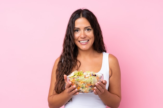 Junge Frau mit Salat über getrennter Wand