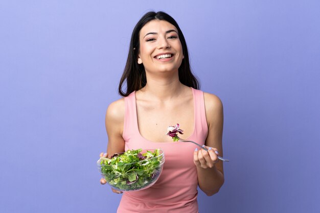 Junge Frau mit Salat über isoliertem Purpur