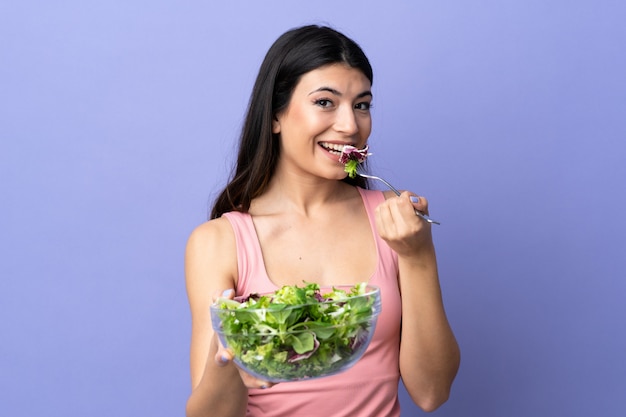 Junge Frau mit Salat über isoliertem Purpur