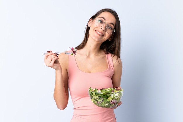 Junge Frau mit Salat über isolierter Wand