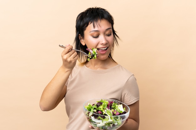 Junge Frau mit Salat über Wand