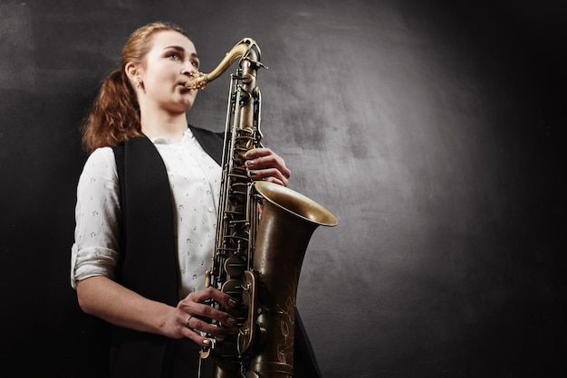 Junge Frau mit Saxophon auf schwarzem Hintergrund