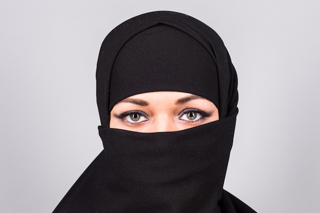 Junge Frau mit schwarzem Niqab im Hintergrund.