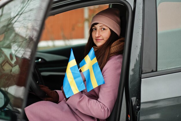 Junge Frau mit schwedischer Flagge auf dem Auto.