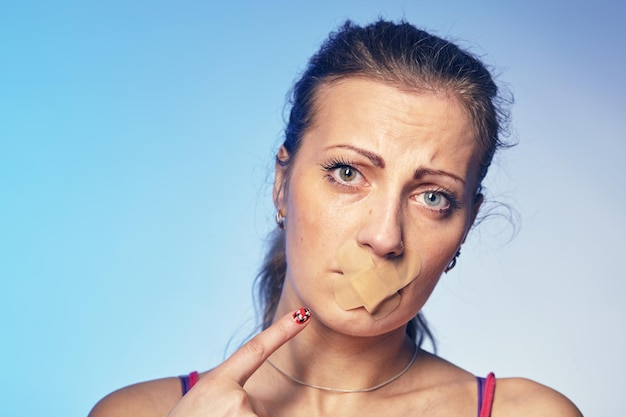 Junge Frau mit seinem Mund mit Klebeband geklebt. Konzept zur Demütigung und Diskriminierung von Frauen