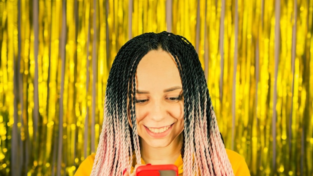 Junge Frau mit senegalesischen Zöpfen, die auf dem Handy surfen Hübsche Frau mit mehrfarbiger Frisur mit Smartphone Close up
