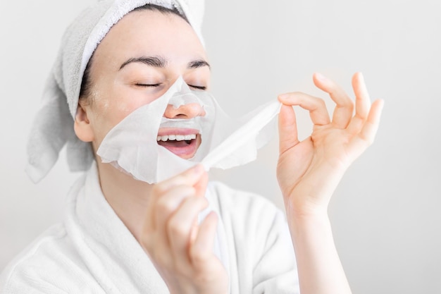 Junge Frau mit Sheet-Maske auf ihrem Gesichts-Spa-Verfahren