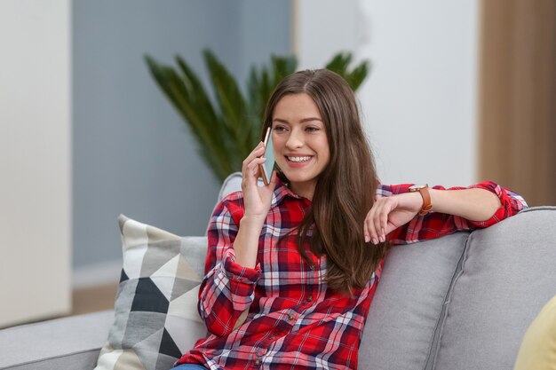 Junge Frau mit Smartphone im Haus