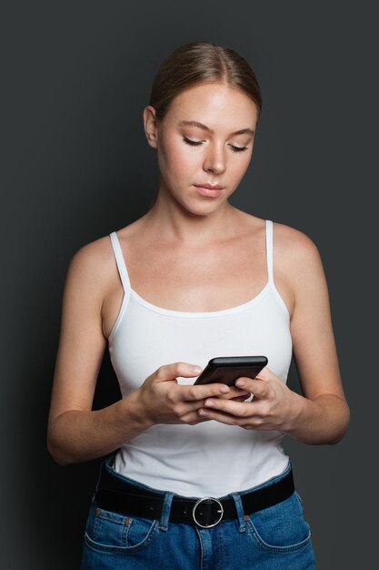 Junge Frau mit Smartphone Mädchen textet auf grauem Hintergrund