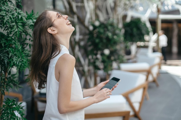 Junge Frau mit Smartphone steht im Restaurantsaal