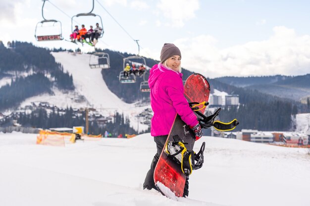 Junge Frau mit Snowboard im Wintersportort