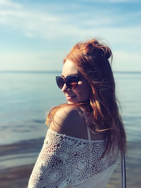 Foto junge frau mit sonnenbrille am strand gegen den himmel